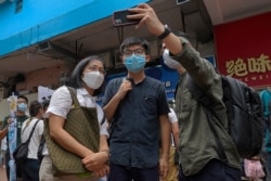 FILE - Hong Kong activist Joshua Wong poses for a photo with supporters, June 20, 2020. Wong said that opposing a draft national security law for Hong Kong “could be my last testimony (while) I am still free.”