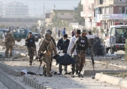 Afghan security forces carry a dead body after a blast in Kabul, Nov. 13, 2019.