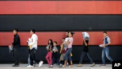 Immigrant families walk along a sidewalk on their way to a respite center after they were processed and released by U.S. Customs and Border Protection, June 24, 2018, in McAllen, Texas. 