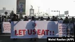 Orang-orang memegang spanduk sebelum berbaris di jalan selama protes di Kabul pada 21 Desember 2021, saat negara itu berjuang dengan krisis ekonomi yang mendalam. (Foto: AFP/Mohd Rasfan)