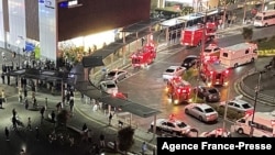 This aerial image shows firefighters and rescue workers gathered outside Kokuryo Station on the Keio Line in Chofu, western Tokyo, Oct. 31, 2021, after a man injured people in a knife and fire attack on a train. (JIJI PRESS / AFP)