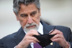 Peru's new interim President Francisco Sagasti takes off his mask after he was designated by Congress to lead the nation, in Lima, Peru, Nov. 16, 2020.