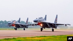 FILE - Two Chinese SU-30 fighter jets take off from an unspecified location to fly a patrol over the South China Sea, in this undated photo released by China's Xinhua News Agency.