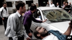 This photo released by the Syrian official news agency SANA shows a Syrian man helping an injured man at the scene after a blast in Damascus, Syria, November 5, 2012. 