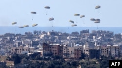 На оваа слика се гледа хуманитарна помош која се фрла над палестинската територија на 10 март 2024 година, во услови на тековен конфликт меѓу Израел и милитантната група Хамас