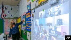 FILE - Jennifer Lepore wears a face mask as she teaches a kindergarten class to students participating remotely and in person at School 16, in Yonkers, N.Y., Oct. 20, 2020.