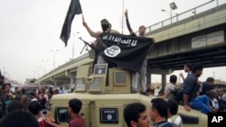 FILE - Islamic State group militants hold up their flag as they patrol in a commandeered Iraqi military vehicle in Fallujah, Iraq, March 30, 2014. 