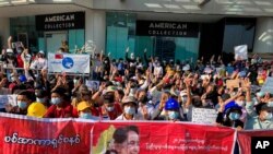 Demonstrators display three-fingered salute, a symbol of resistance at an intersection in Yangon, Myanmar, Feb. 10, 2021. 