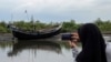 FILE - An Acehnese woman uses her cell phone to take a picture of a boat that carried a group of ethnic Rohingya after it washed ashore in Bireuen, Aceh province, Indonesia, April 20, 2018. 