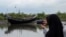 FILE - An Acehnese woman uses her cell phone to take a picture of a boat that carried a group of ethnic Rohingya after it washed ashore in Bireuen, Aceh province, Indonesia, April 20, 2018. 