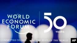 A man silhouettes in front of the logo of the World Economic Forum in Davos, Switzerland, Sunday, Jan. 19, 2020. 