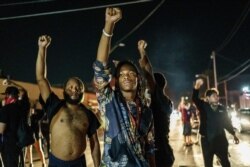FILE - Protesters raise their fists during a demonstration against the shooting of Jacob Blake in Kenosha, Wisconsin, Aug. 26, 2020.