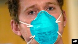 FILE - Registered nurse Scott McGieson wears an N95 mask as he walks out of a patient's room in the acute care unit of Harborview Medical Center, Jan. 14, 2022, in Seattle. 