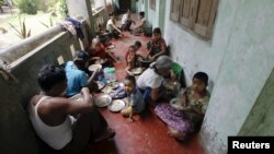 People eat food distributed at a Buddhist monastery used as a collective shelter for those displaced by recent violence in Sittwe, June 17, 2012.