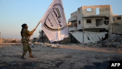 A Turkish-backed Syrian rebel holds the flag of his division in the northwestern border town of al-Bab on Feb. 23, 2017, after they fully captured the town from the Islamic State (IS) group.