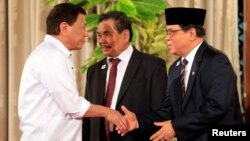 Philippine President Rodrigo Duterte, left, greets Moro Islamic Liberation Front (MILF) chairperson Al Haj Murad Ebrahim, right, while Mohagher Iqbal, MILF peace panel chairman, looks on during a handover of a draft law of the Bangsamoro Basic Law (BBL) in a ceremony at the Malacanang presidential palace in metro Manila, Philippines, July 17, 2017. 
