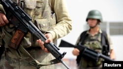 FILE - Turkish soldiers stand guard at a check point on the main road between Mardin and Cizre in southeastern Turkey, Sept. 9, 2015. 