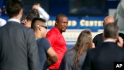 Federal agents hold a detainee, center, in Los Angeles after raids, Aug. 22, 2019. U.S. authorities have an indictment charging 80 people with participating in a conspiracy to steal millions of dollars through fraud schemes and laundering the funds.