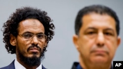 Ahmad Al Mahdi Al Faqi, left, enters the court room for his initial appearance at the International Criminal Court in The Hague, Netherlands, Sept. 30, 2015. 