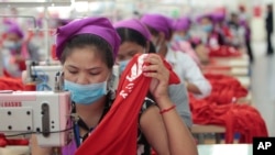 FILE PHOTO - Garment workers sew clothes in a factory as they wait for a visit by Prime Minister Hun Sen outside of Phnom Penh, Cambodia, Wednesday, Aug. 30, 2017. (AP Photo/Heng Sinith)
