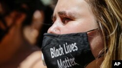 A women wears a protective mask as she joins protesters near Trump Tower as part of a solidarity rally calling for justice over the death of George Floyd, and to highlight police brutality nationwide, June 12, 2020, in New York.
