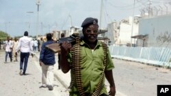 FILE - A Somali soldier patrols near the site of a car bomb outside the UN's office in Mogadishu, Somalia, July 26, 2016.