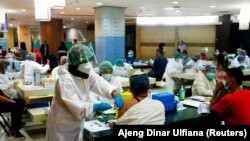 Seorang pedagang menerima dosis vaksin COVID-19 merek Sinovac Biotech China dalam program vaksinasi di Pasar Tanah Abang, pada 17 Februari 2021. (Foto: Reuters/Ajeng Dinar Ulfiana)