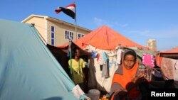 FILE - A Yemeni refugee stands in front of her makeshift shelter at a temporary camp in Somalia's capital, Mogadishu, Dec. 16, 2015. 