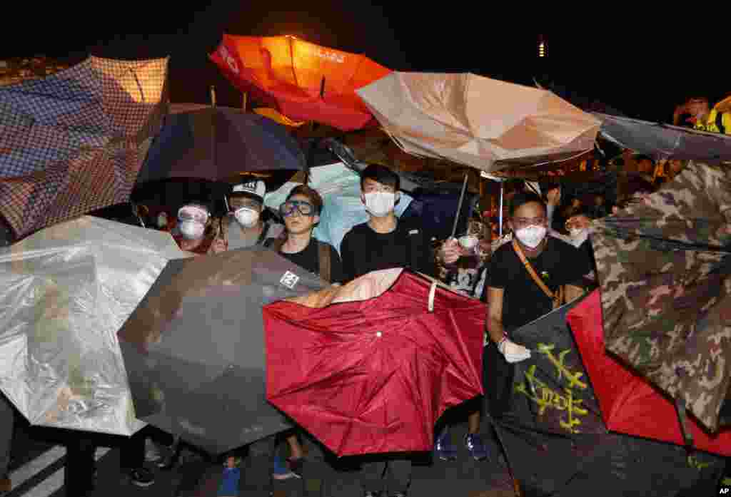 Protesters use umbrellas to block the pepper spray by police officers outside government headquarters in Hong Kong's Admiralty, Oct. 15, 2014. 