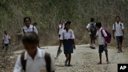 In this Oct. 22, 2018, file photo, students walk on dirt road after school in O'of village in West Timor, Indonesia. Children in this impoverished region of Indonesia often must walk long distances to school. 