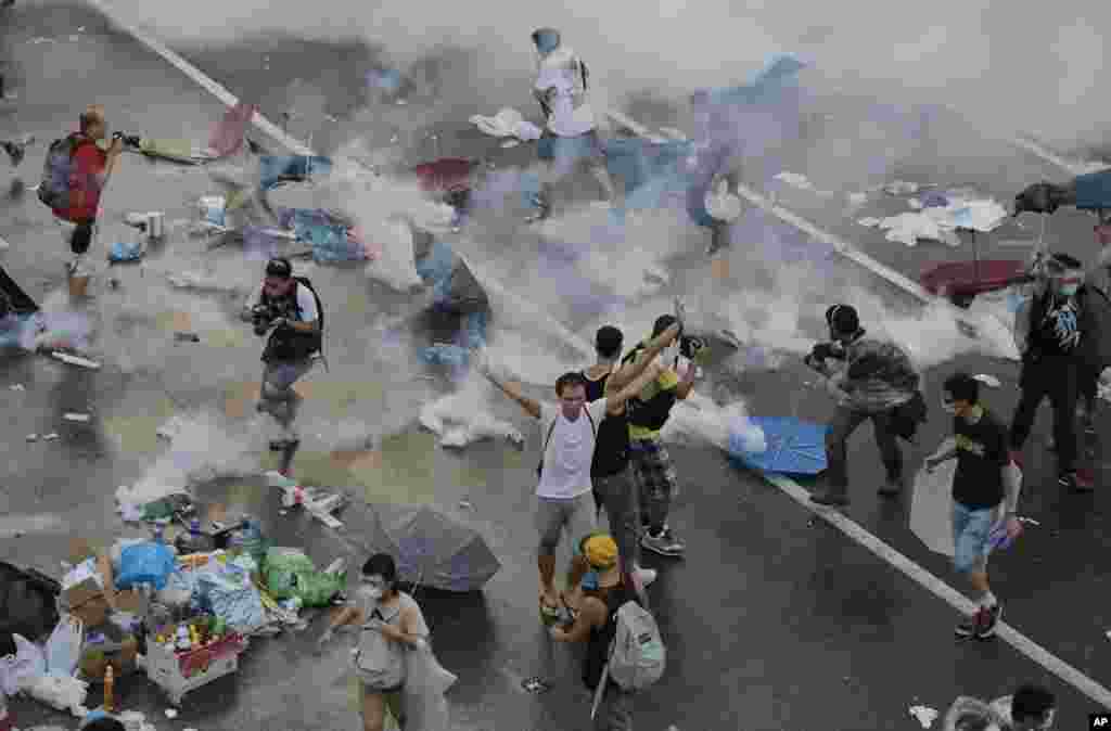 Protesters walk through tear gas used by riot police after thousands of people blocked a main road at the financial central district in Hong Kong.