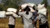 FILE - Ethiopians who fled the ongoing fighting in Tigray region, carry supplies at the Um-Rakoba camp on the Sudan-Ethiopia border, in Kassala state, Sudan, Dec. 17, 2020.