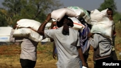 FILE - Ethiopians who fled the ongoing fighting in Tigray region, carry supplies at the Um-Rakoba camp on the Sudan-Ethiopia border, in Kassala state, Sudan, Dec. 17, 2020.