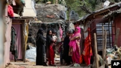 Pengungsi Rohingya berdiri di luar kamp darurat mereka di pinggiran Jammu, India, Minggu, 7 Maret 2021. (Foto: AP)