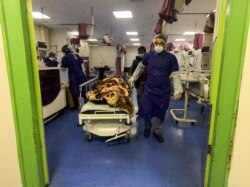 FILE - A medic moves a patient in a ward dedicated for people infected with the coronavirus at Forqani Hospital, in Qom, 125 kilometers south of Tehran, Iran, Feb. 26, 2020.