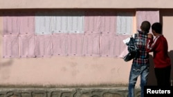 FILE - Afghan boys look on a preliminary list taped to the wall of a polling station in Kabul, April 7, 2014. 