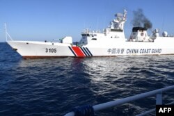 Sebuah kapal Garda Pantai China mengawasi kapal BRP Datu Tamblot dari Biro Perikanan dan Sumber Daya Perairan Filipina (BFAR) di sekitar Scarborough Shoal yang diklaim oleh China, di wilayah perairan yang diperebutkan di Laut China Selatan. (Foto: AFP)