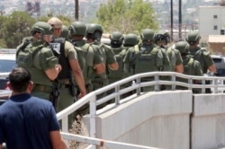 Law enforcement officers make their way along a walkway to the scene of a shooting at a shopping mall in El Paso, Texas, Aug. 3, 2019.