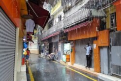 FILE - A man shelters from the rain in Guangzhou's Xiaobei neighborhood, nicknamed "little Africa", as it starts to recover from a lockdown after the outbreak of the coronavirus disease, in Guangdong province, China, June 17, 2020.