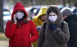 People wearing protective masks walk on street in Minsk, Belarus, Feb. 28, 2020. Belarus, Lithuania and New Zealand have reported their first cases of coronavirus.