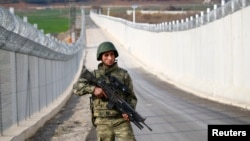 FILE - A Turkish soldier patrols along a wall on the border line between Turkey and Syria near the southeastern city of Kilis, Turkey, March 2, 2017.