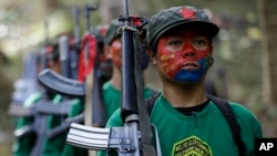 FILE - Мembers of the New People's Army communist rebels, with their face painted to conceal their identities, march with their firearms at their encampment in the Sierra Madre mountains southeast of Manila, Philippines, Nov. 23, 2016.