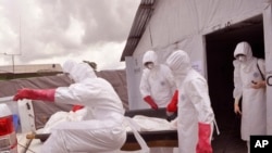 FILE - health workers wearing Ebola protective gear remove the body of a man they suspect died from the Ebola virus, at a USAID, American aid Ebola treatment center on the outskirts of Monrovia, Liberia, Nov. 28, 2014.