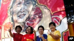 Members of Myanmar opposition National League for Democracy party pose for photos in front of a graffiti art depicting party leader Aung San Suu Kyi created by artist Arker Kyaw outside the party's headquarters in Yangon, Myanmar, Nov 13, 2015.