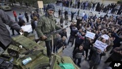 An armed man stands on top of a captured tank in Zawiya, 30 miles (50 kilometers) west of Tripoli, in Libya Sunday, Feb. 27, 2011.