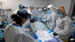 Dr. Joseph Varon, top with JV on shield, leads a team as they tried without success to save the life of a patient inside the Coronavirus Unit at United Memorial Medical Center, July 6, 2020, in Houston. 