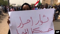 A Sudanese protester holds an Arabic placard that reads: "Free revolutionaries will continue the path," during a demonstration against the military council, in Khartoum, Sudan, June 30, 2019. 