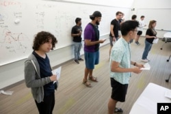 Diego Fonseca, left, and his fellow students uses their bodies to plot their location on a graph based on the number they are holding during a summer math boot camp session on Thursday, Aug. 1, 2023 at George Mason University in Fairfax. Va. (AP Photo/Kevin Wolf)