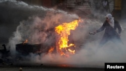 An anti-government protester tries to set fire to a barricade while up against the police's water cannon during clashes in Caracas, March 12, 2014.