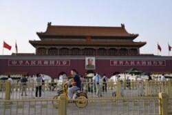 People cycle past Tiananmen gate on the eve of the 31st anniversary of the June 4, 1989 crackdown on pro-democracy protests, in Beijing on June 3, 2020.